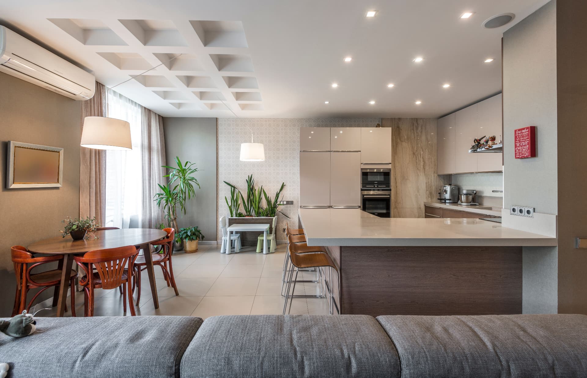 Open-plan kitchen, dining and living space with feature and recessed lighting